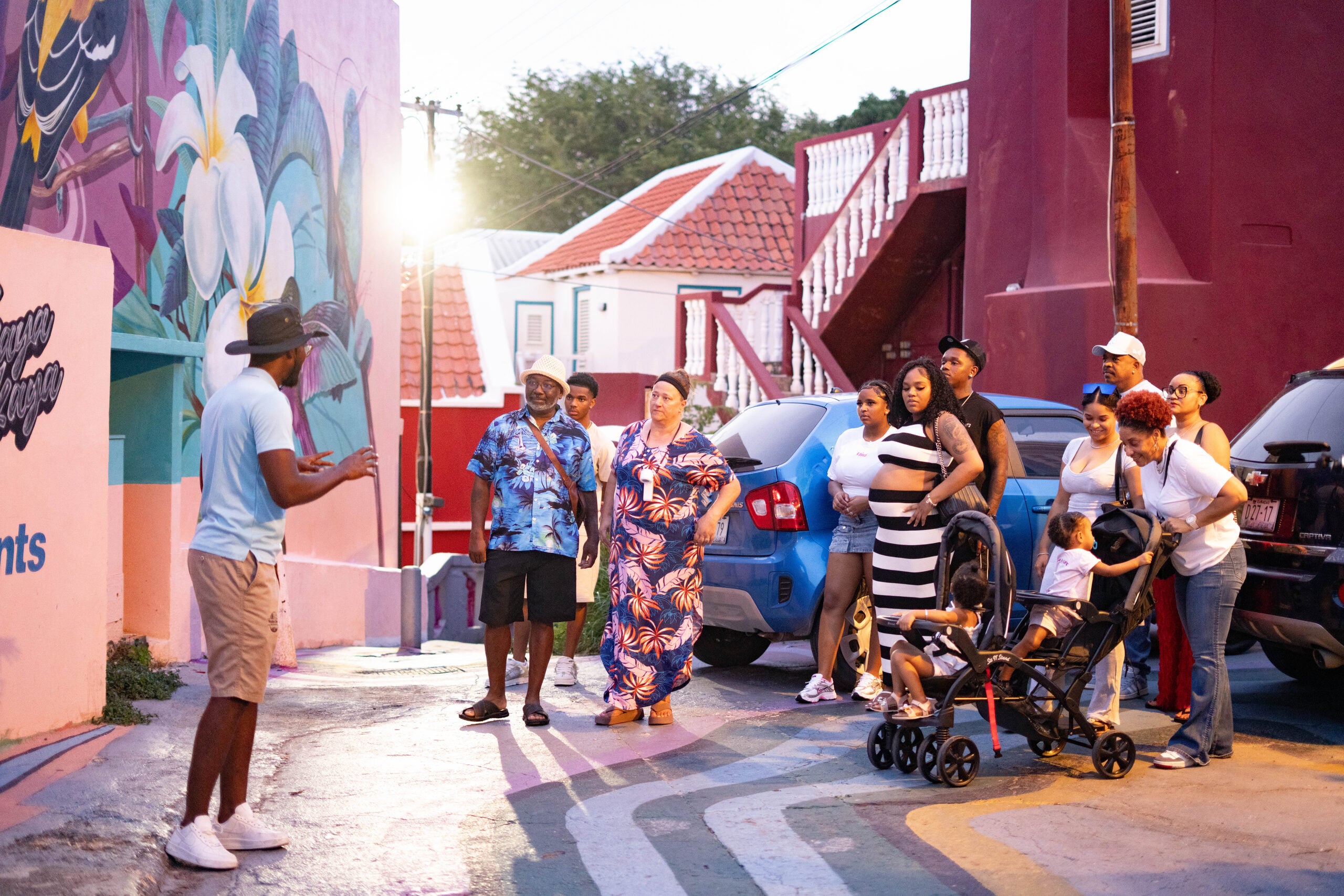 Our guide telling a story to a family group beside Otrobanda street-art murals at golden hour