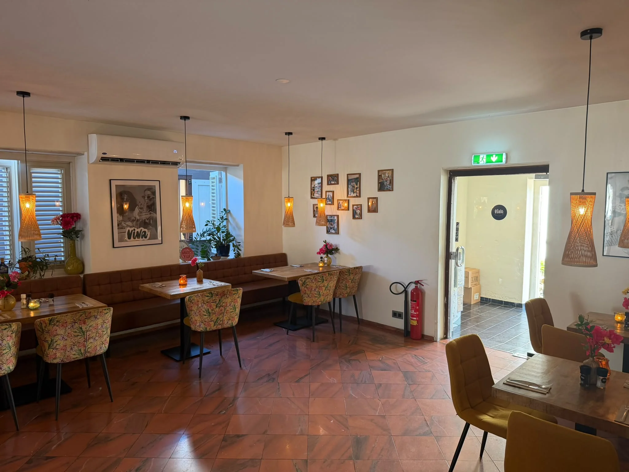 Der klimatisierte Speisesaal im „Viva“ verfügt über Sitzbänke, Stühle mit Blumenmuster und gerahmte Fotos an den Wänden.